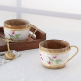 Handmade bamboo floral tea cup set of 2 with pink blossom artwork, styled on a table with a spoon for tea serving and dining