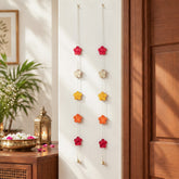 Multicoloured bamboo flower hangings, festive room decor styled beside a doorway