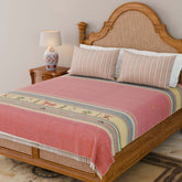 Handwoven Bawan Buti cotton bedcover in red draped over a wooden bed with tassel details in a traditional yet contemporary bedroom setting