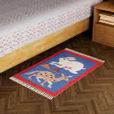 Blue handwoven cotton dhurrie with camel and rabbit motifs styled as a colourful floor accent in a living space