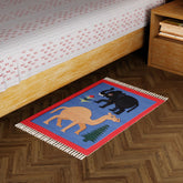 Blue handwoven cotton dhurrie with camel and elephant motifs styled in a living space as a colourful floor accent
