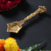 Brass hawan spoon with Naga or snake motif handle styled in a traditional puja setup, showcasing spiritual and festive use