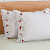 Brown floral vine embroidered pillow cases arranged on a bed for warm and elegant bedroom styling