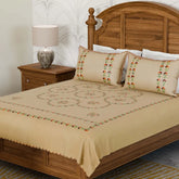 Brown cotton king-size bedcover with multicoloured Bengal chikankari hand embroidery and matching pillow cases styled in a warm bedroom setting