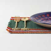 Handmade green Madhurkathi table mats styled on a dining table with cutlery and ceramic plates, creating an elegant table setting