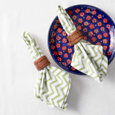 Green and white zigzag block printed cotton napkins styled on a dining table with tableware for an elegant table setting