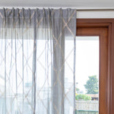 Grey Chanderi sheer curtain styled on a window allowing soft natural light into the room