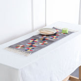 Grey handwoven cotton floor runner with colourful geometric floral motifs styled in a table as a decorative home accent