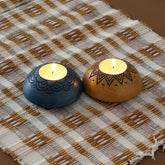 Handcarved wooden T-light holder set of 2 in blue and yellow displayed with lit tea lights, adding warmth to handmade decor and festive settings