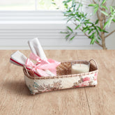 Handmade rectangular wicker storage basket with pink floral decoupage artwork holding home accessories on a table, ideal for gifting and organisation