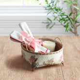 Handmade wicker storage basket with pink floral decoupage artwork holding home accessories on a table, ideal for gifting and organisation