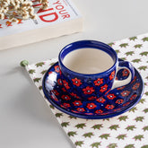 Handpainted floral ceramic mug and saucer set in blue and red colours, beautifully styled for coffee, tea, and elegant table settings