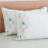 Multicoloured floral vine embroidered pillow cases styled on a bed for vibrant and elegant bedroom decor