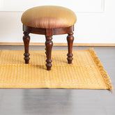 Handmade mustard abstract dhurrie rug styled in a reading corner, showcasing traditional weaving and block printing artistry