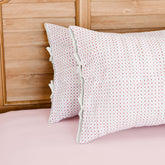 Hand block printed cotton pillow cover set with pink and red dotted line patterns on a white base, styled on a bed with coordinated cotton bed linen