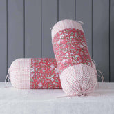 Red hand block printed bolster cover set styled on a bed adding warmth, colour and handcrafted charm to home decor