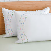 Rose vine embroidered pillow cases styled on a bed adding a handcrafted touch to elegant bedroom decor