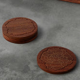 Rosewood coaster set with marigold floral brass inlay, styled on a table top making an elegant corporate gift