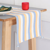 Handwoven cotton table runner with blue, orange, and white striped pattern and tassels styled on a dining table, creating a vibrant table setting and dining table décor