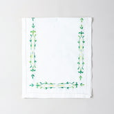 Folded Bengal chikankari runner showcasing green floral vine embroidery on soft white cotton table linen