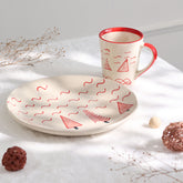 White and red Christmas tree ceramic breakfast set featuring a hand-painted plate and mug styled on a festive table setting