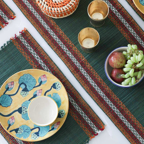 Dining table setting with a green Madurkathi table runner and placemats set featuring natural river grass weave and handcrafted table decor