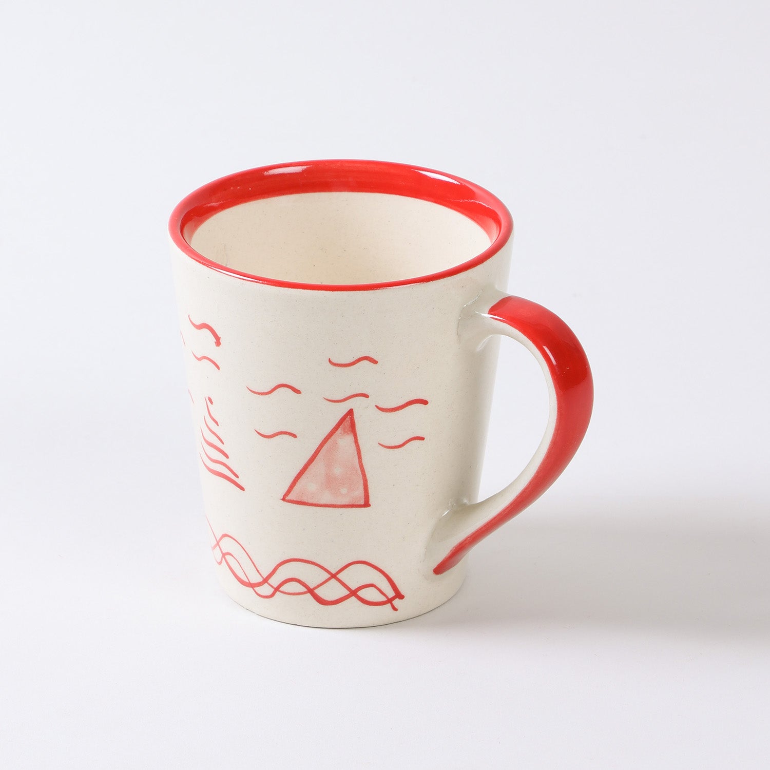 Angled view of a hand-painted Christmas ceramic mug featuring festive red tree artwork and a glossy finish