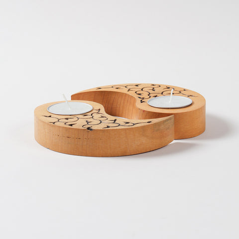 Side angled view of yellow wooden tea light candle holders with carved leaf motifs, displayed with unlit T-lights on a plain background