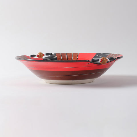 Side profile of a hand-painted ceramic serving bowl featuring earthy red, brown, black, and white colours with decorative wooden bead embellishments