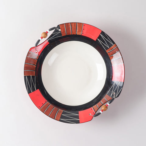 Top view of a handmade ceramic bowl with a white interior, bold African-inspired geometric rim patterns, and decorative wooden bead accents