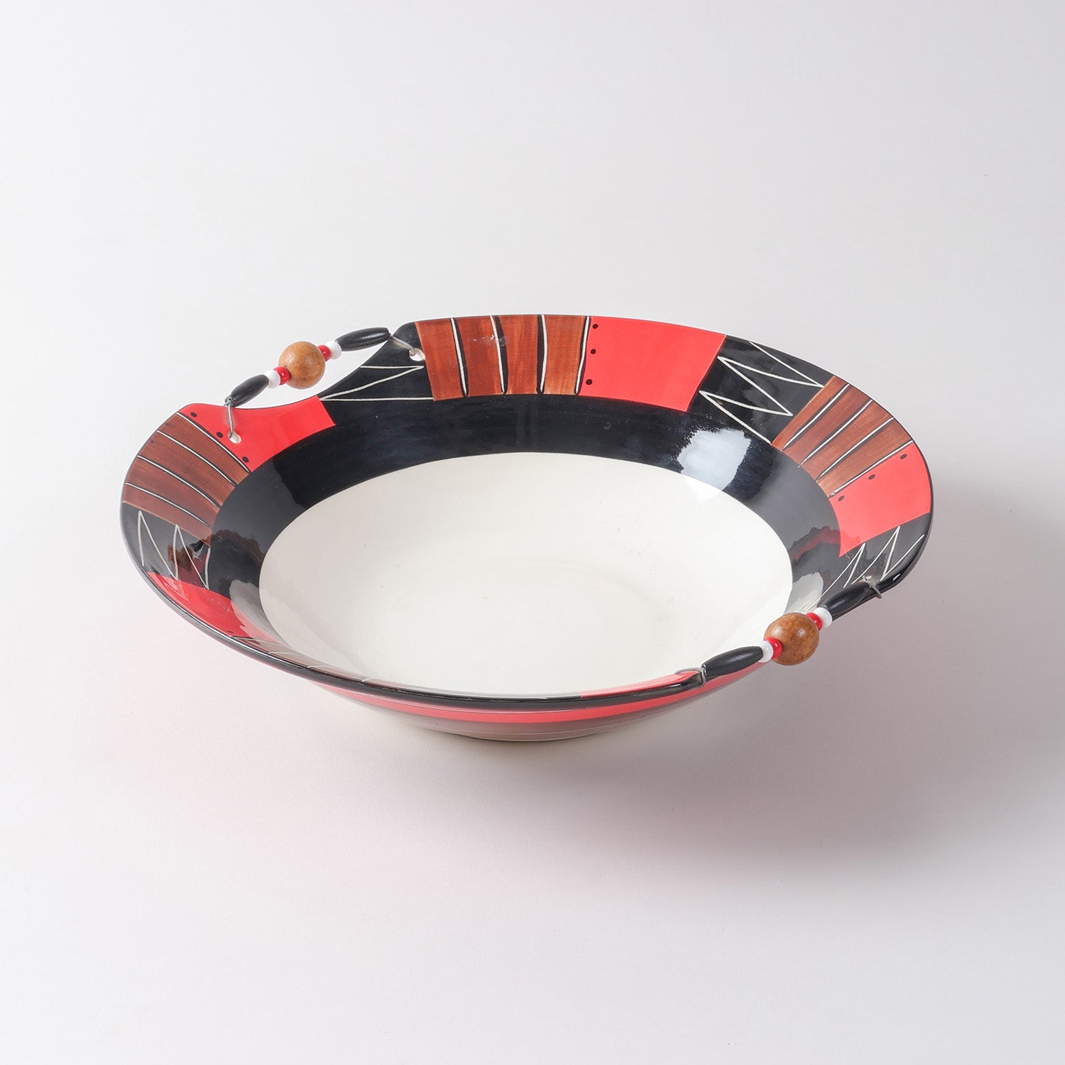 Handmade ceramic serving bowl featuring abstract African-inspired patterns in red, black, brown, and white, finished with decorative wooden beads along the rim