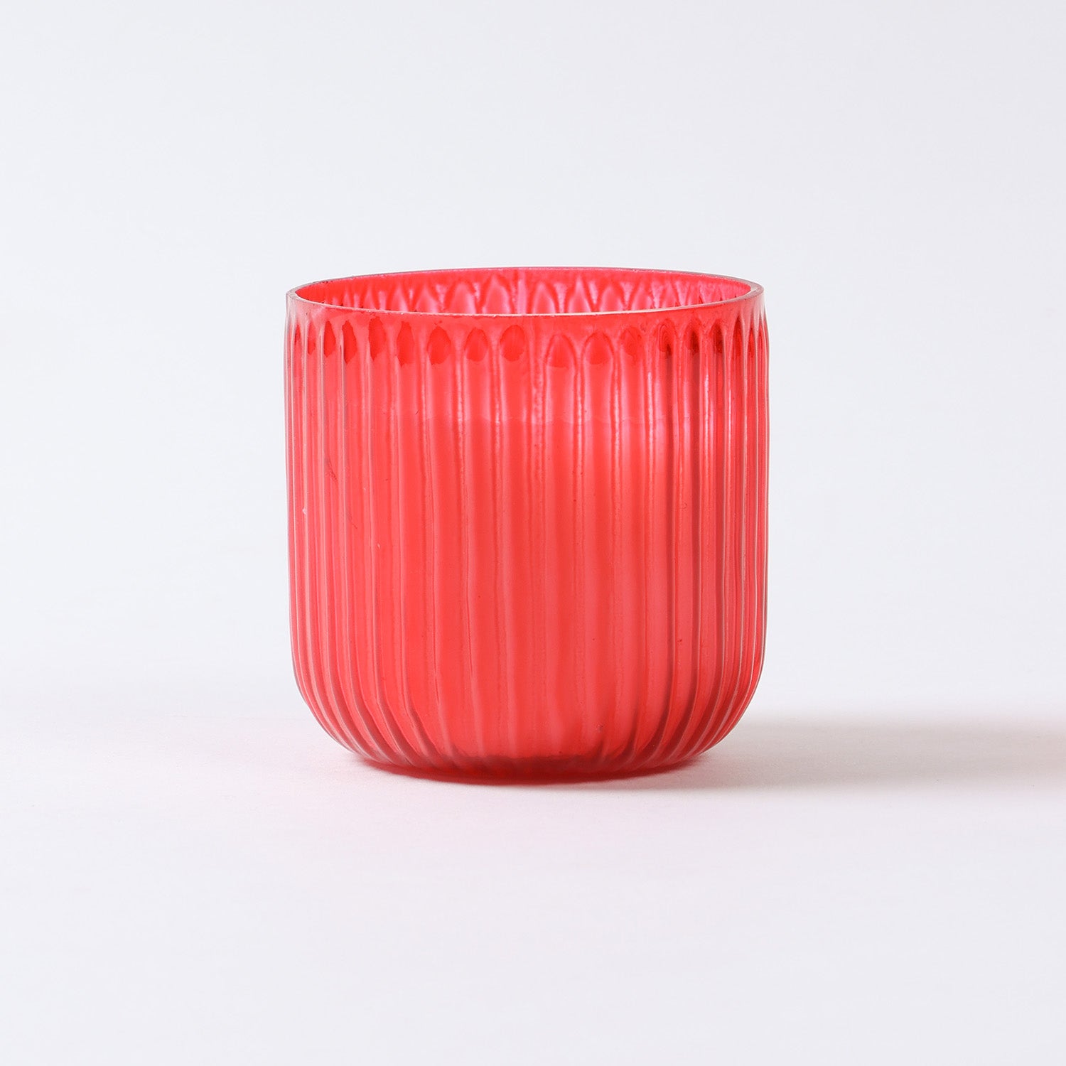 Eye-level view of ribbed red glass candle filled with fragrant soy wax for home ambience