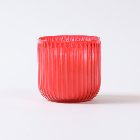 Eye-level view of ribbed red glass candle filled with fragrant soy wax for home ambience