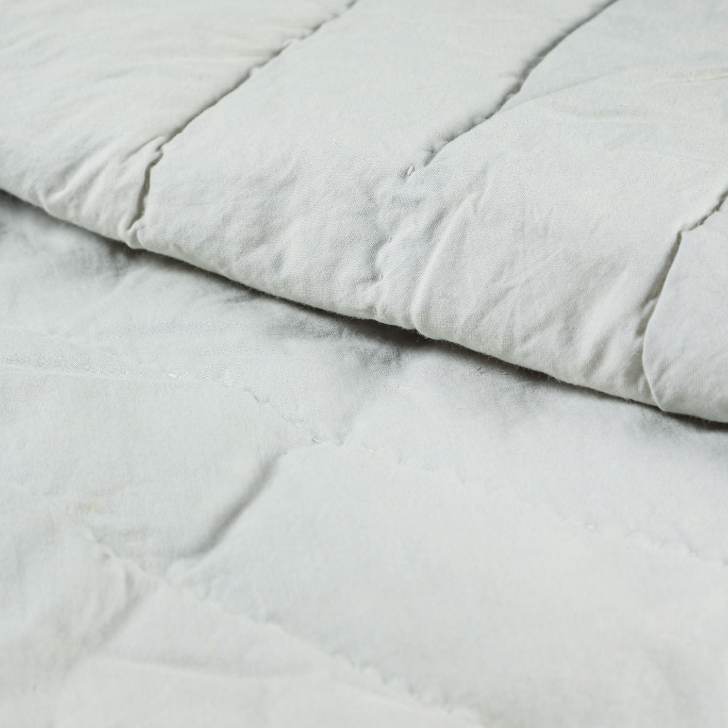 Close-up of floral block printed cotton quilted bedspread showing stitching details, breathable cotton fabric, and yellow piping edge