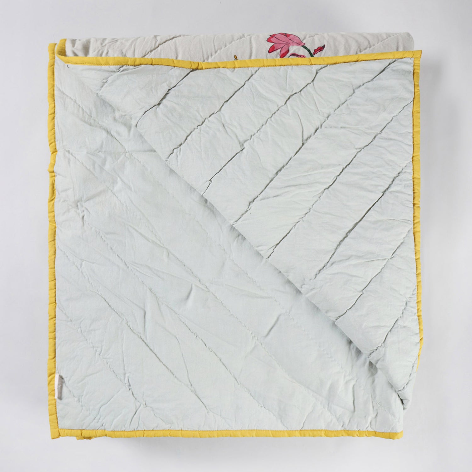 Reversible cotton quilted bedspread displaying both front and back designs with traditional block printed floral motifs