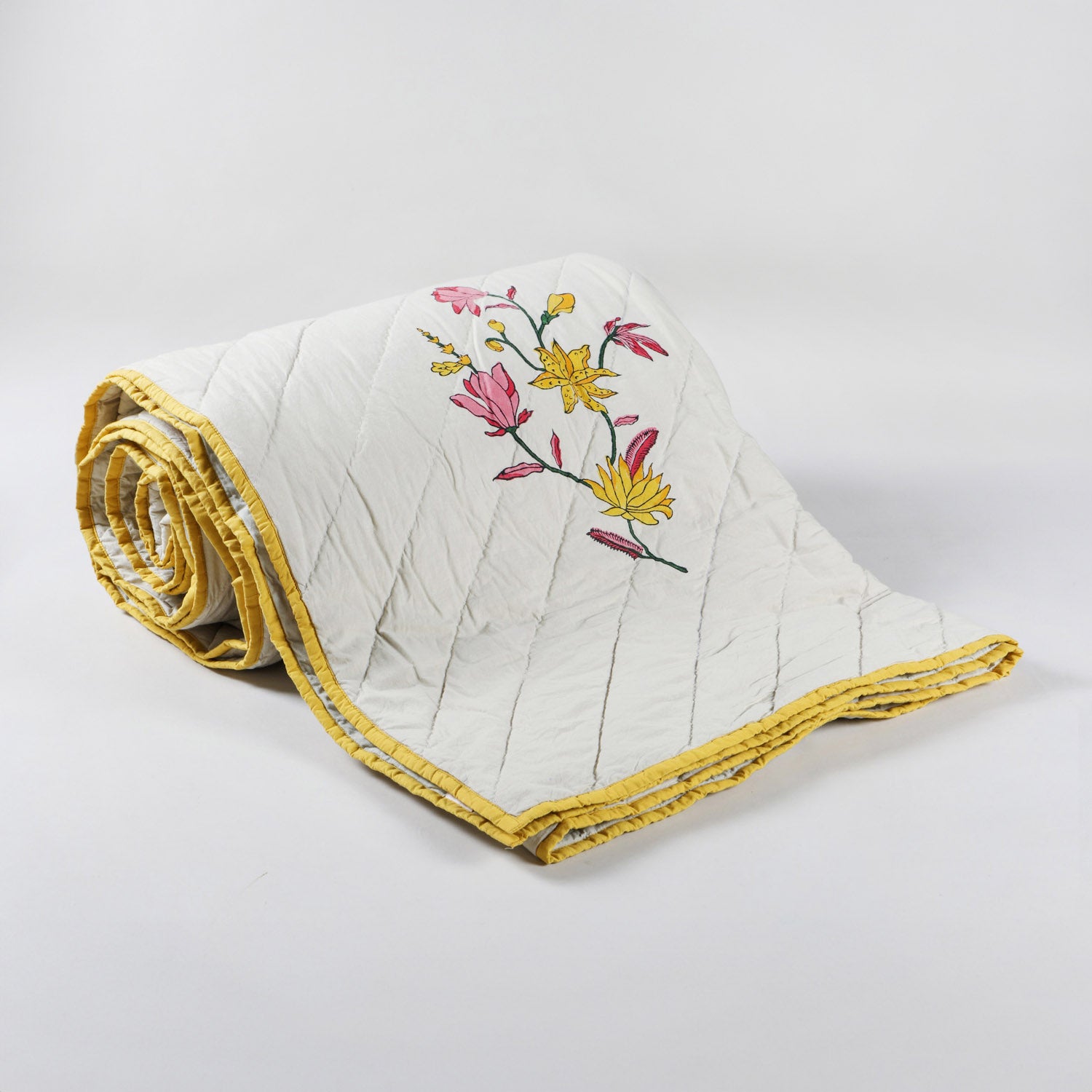 Hand block-printed cotton quilted bedspread with repeated floral motifs and sage green background  with a solid yellow fabric border 