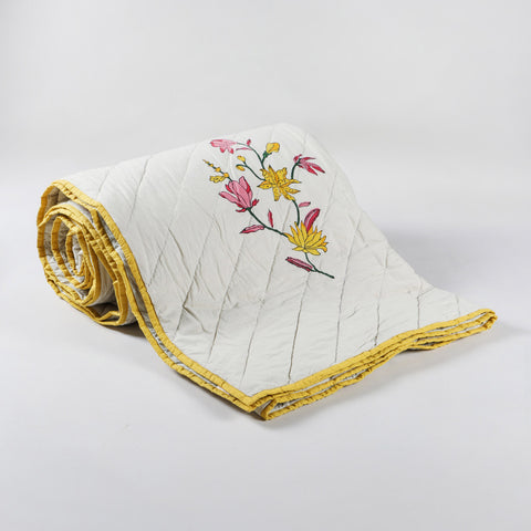 Hand block-printed cotton quilted bedspread with repeated floral motifs and sage green background  with a solid yellow fabric border 