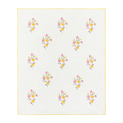 Full view of a king size hand block printed cotton quilted bedspread with pink and yellow floral motifs on a sage green base