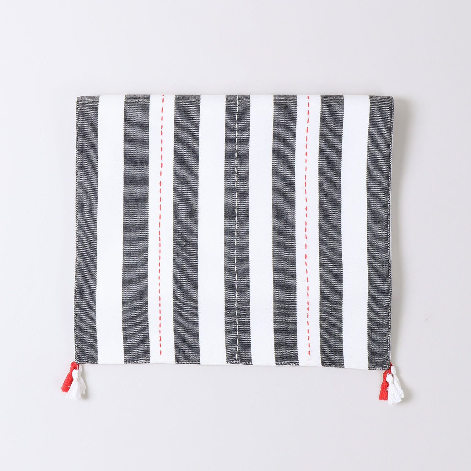 Folded black and white striped cotton table runner showcasing handwoven craftsmanship and decorative tassel detailing