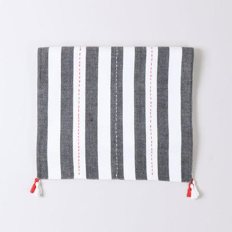 Folded black and white striped cotton table runner showcasing handwoven craftsmanship and decorative tassel detailing