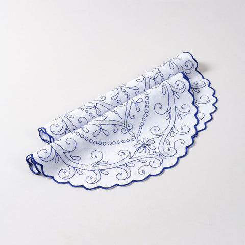 Folded set of two white cotton table mats featuring blue chikankari floral embroidery and scalloped edges, showcasing handcrafted detailing and premium cotton table linen quality