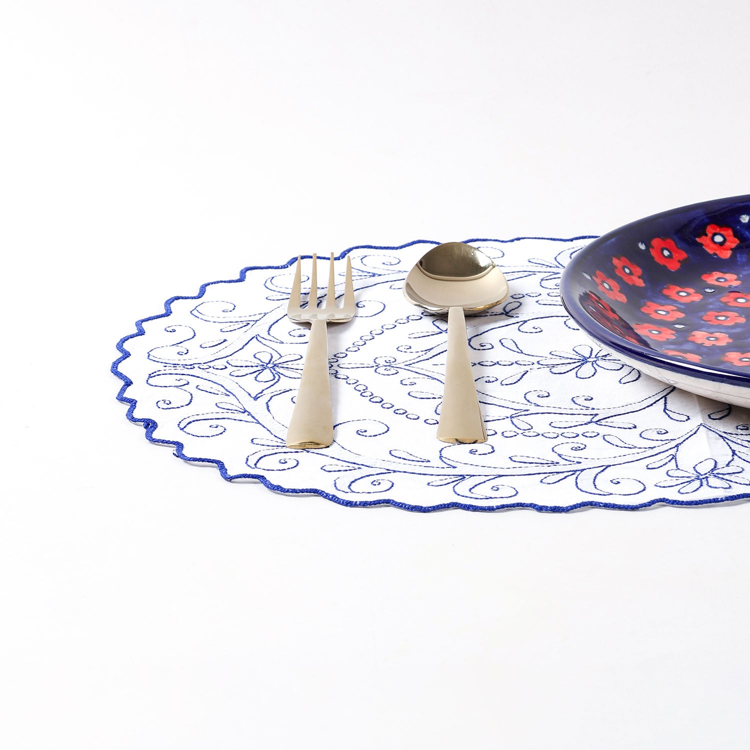 Embroidered cotton placemat arranged with dinnerware on a dining table, creating a refined and elegant table setting