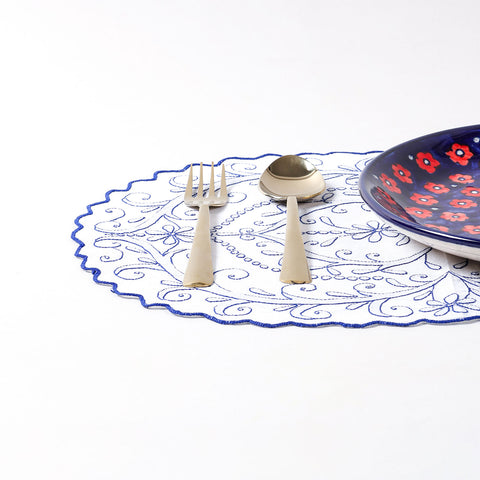 Embroidered cotton placemat arranged with dinnerware on a dining table, creating a refined and elegant table setting
