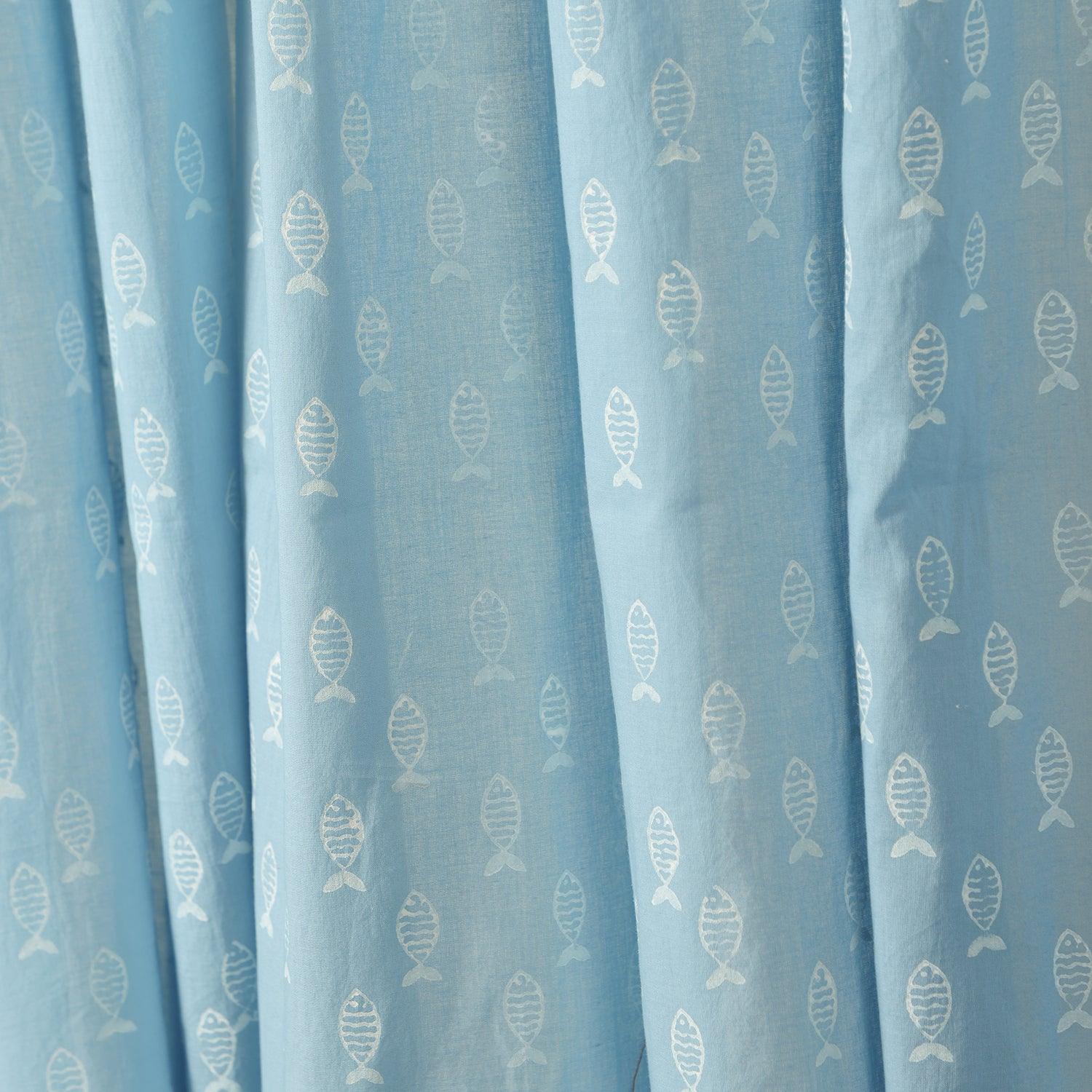 Close-up of hand block-printed fish motifs on soft blue hand dyed mulmul cotton curtain fabric.