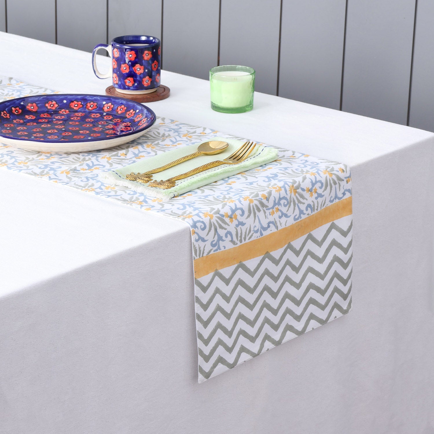Blue floral block printed table runner styled on a dining table with coordinated table linens and dinnerware