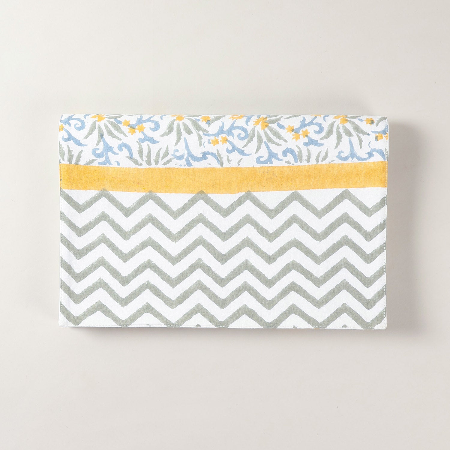 Folded cotton table runner featuring blue and yellow floral block printed motifs on a white base