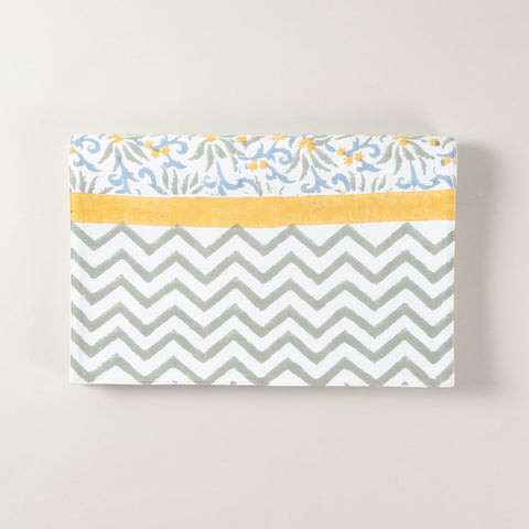 Folded cotton table runner featuring blue and yellow floral block printed motifs on a white base