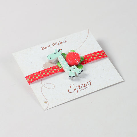 Angled view of the handmade Blue Giraffe Wooden Kids Rakhi with red ribbon attached to a festive Best Wishes card for Raksha Bandhan gifting