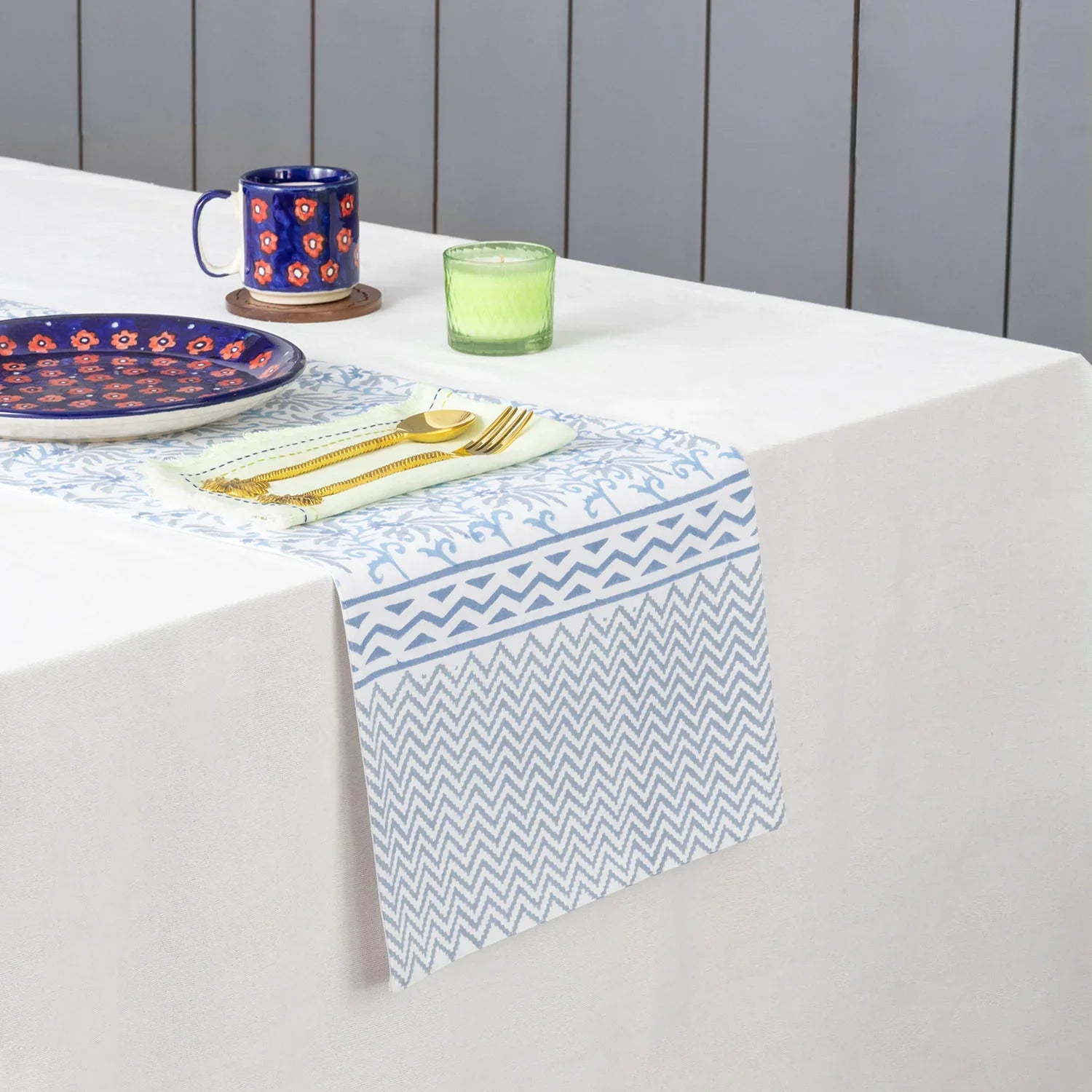 Blue lily hand block printed cotton table runner styled on a dining table with coordinated tableware and home decor accents