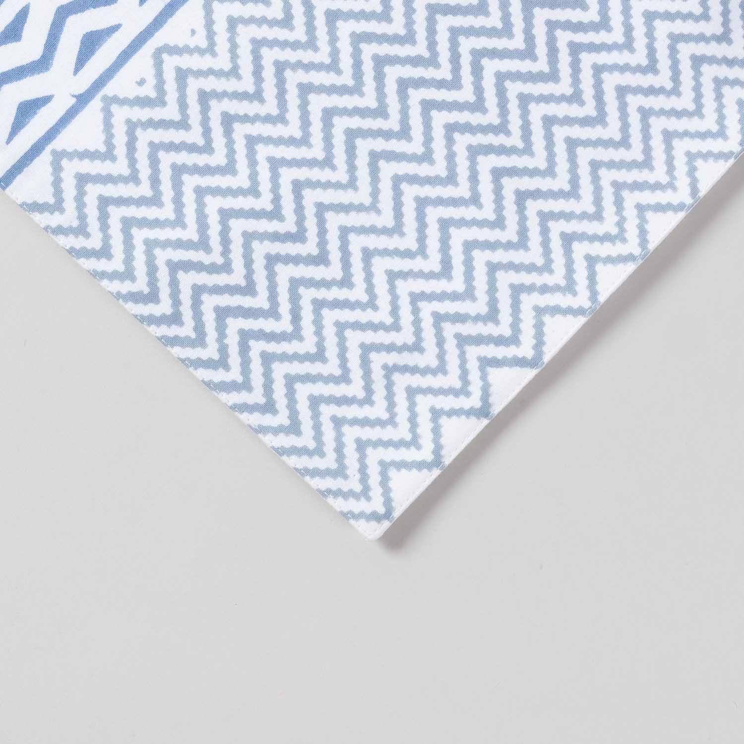 Close-up corner view of a blue lily hand block printed table runner highlighting floral vine motifs and  zig-zag pattern on cotton texture